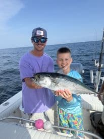 A young angler proudly displays a large fish while fishing on a boat, enjoying a day out on the water.