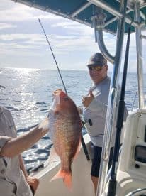 Angler displaying a vibrant Red Snapper while fishing offshore, showcasing a successful day on the water.