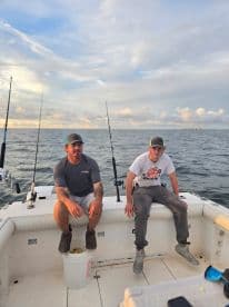 Two anglers relaxing on the boat's interior, preparing for a fishing trip in open waters.