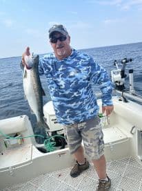 An angler proudly displaying a large trout while fishing on a boat, showcasing a successful day on the water.