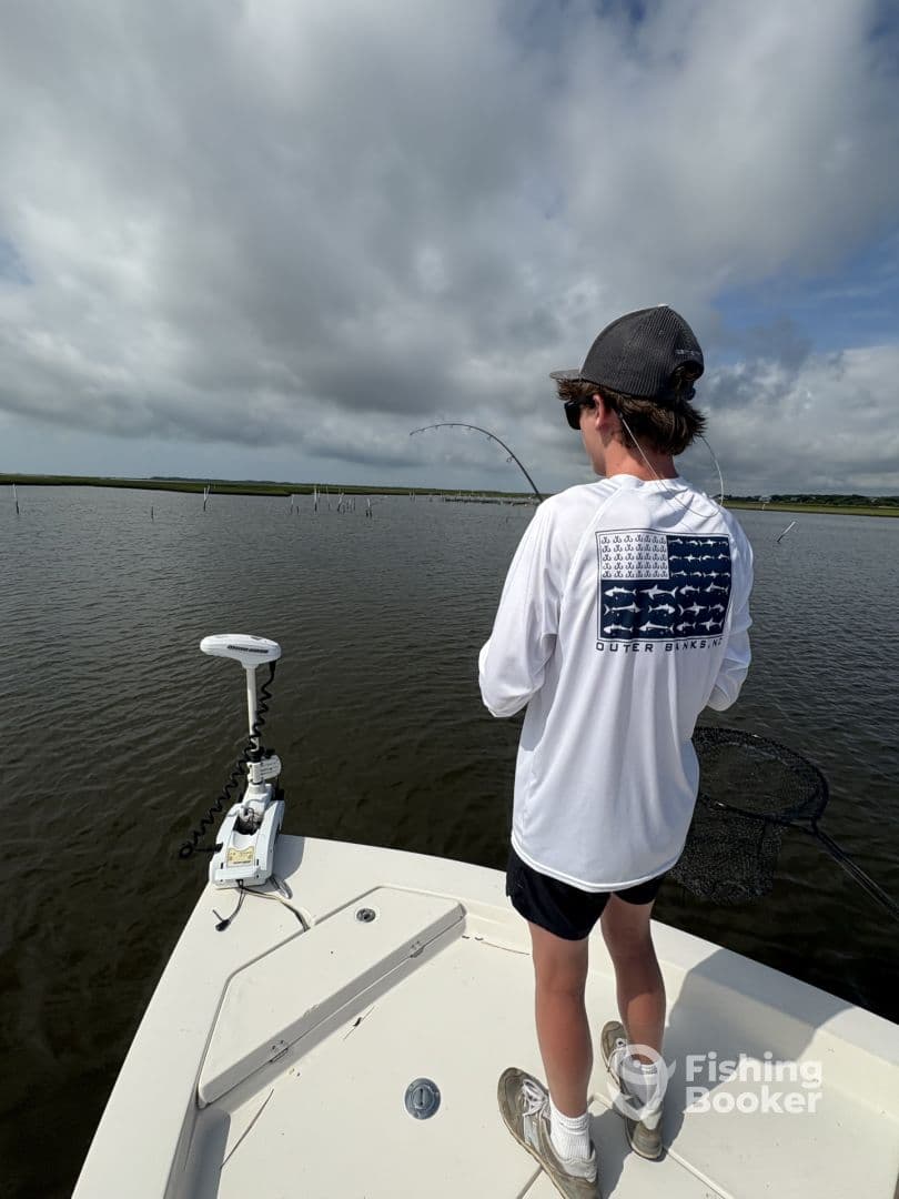 A young angler casting from a boat in a calm waterway, showcasing the excitement of fishing in a scenic environment.