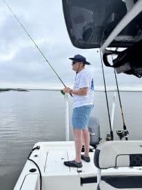 An angler casting a line from a modern fishing boat in calm waters, showcasing the excitement of fishing in a serene environment.