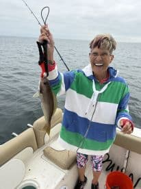 An enthusiastic angler proudly displaying a freshly caught fish while fishing on a boat, showcasing a vibrant fishing environment.