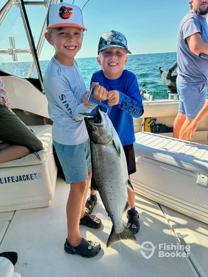 Two young anglers proudly displaying a large fish on a fishing boat, enjoying a day out on the water.