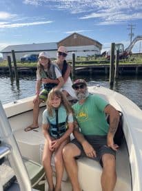 A family enjoying a day on a boat, with two children and an adult seated comfortably, showcasing a fun and relaxed fishing environment.