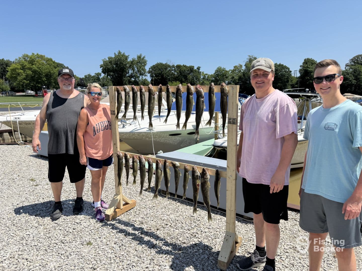 A group of four anglers proudly displaying their catch of fish on a board at the marina, showcasing a successful day of fishing.