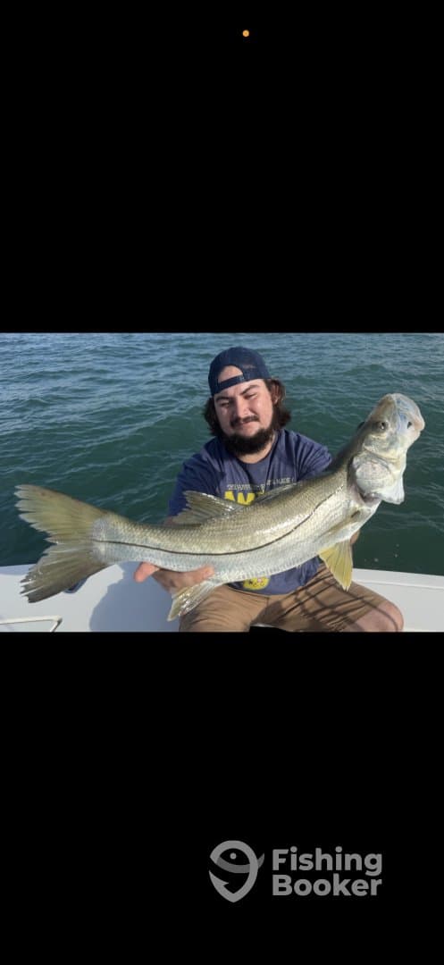 Angler proudly displaying a large Snook while on a boat, showcasing a successful fishing trip.