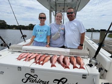A group of anglers proudly displaying their catch of Red Snapper on a boat after a successful fishing trip.
