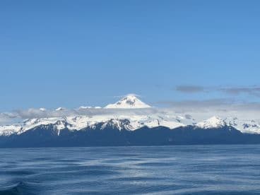 A scenic view of snow-capped mountains under a clear blue sky, showcasing the stunning natural beauty of the fishing environment.