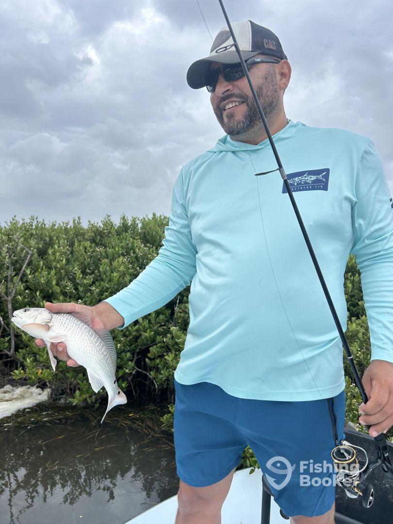 An angler proudly displaying a freshly caught fish while fishing in a mangrove area, showcasing the thrill of the catch.