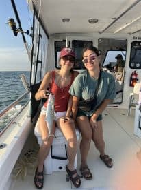 Two young anglers proudly displaying a caught fish while enjoying a fishing trip on a charter boat.