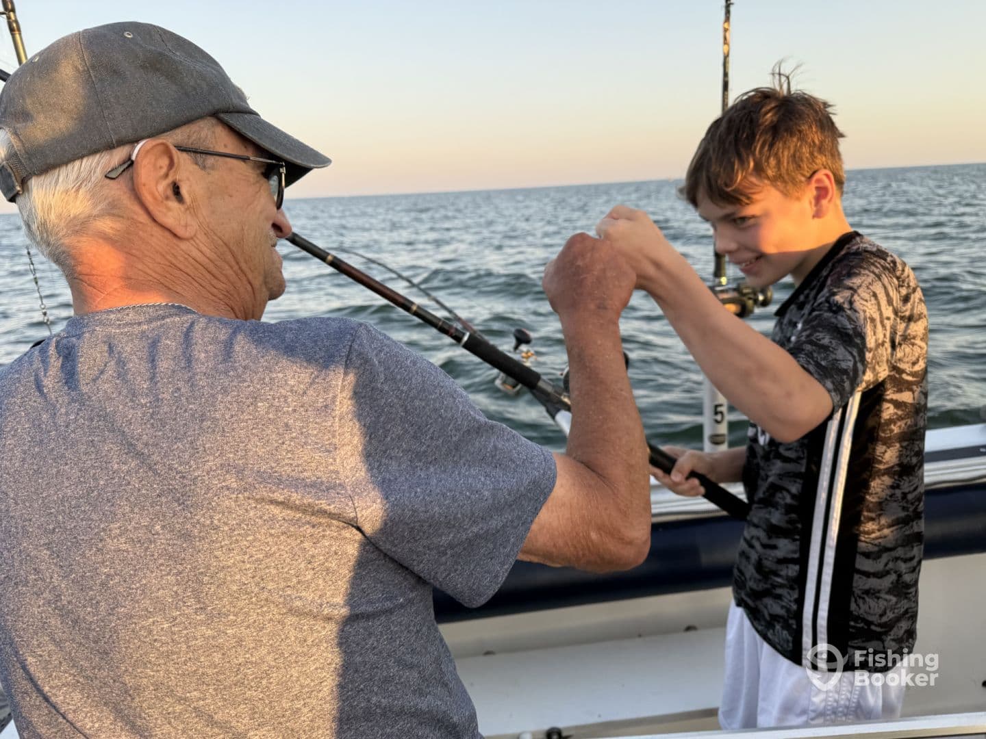 A young angler and an older gentleman share a moment of excitement while fishing on a boat, showcasing the joy of fishing together in open waters.