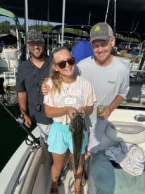 A young angler proudly displaying a large fish on a boat, surrounded by family members after a successful fishing trip.