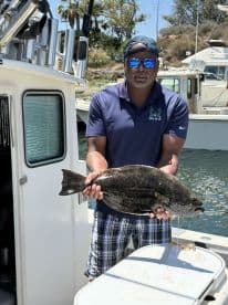 Angler proudly displaying a large Halibut on a fishing boat, showcasing a successful day on the water.