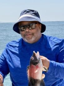 An angler proudly displaying a freshly caught fish while enjoying a sunny day on the water.