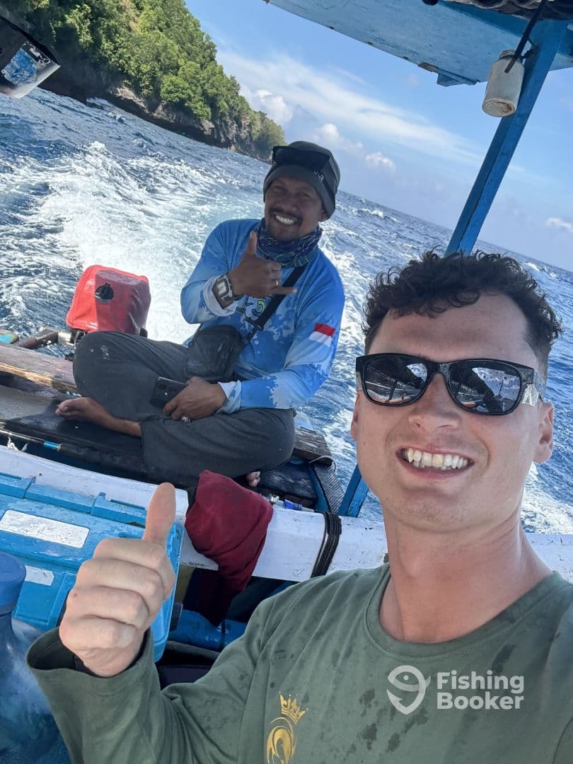 Two anglers enjoying a fishing trip on a small boat, showcasing a scenic ocean backdrop and a relaxed atmosphere.
