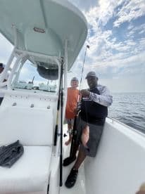 A young angler and an adult proudly displaying a freshly caught Snapper aboard a fishing boat, enjoying a day on the water.