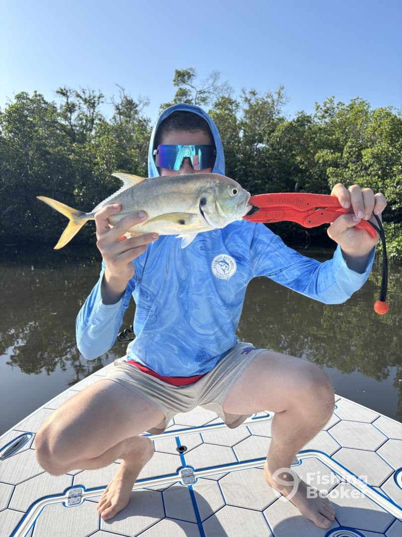 A young angler proudly displaying a Silver Jack while fishing in a mangrove area, showcasing the excitement of a successful catch.