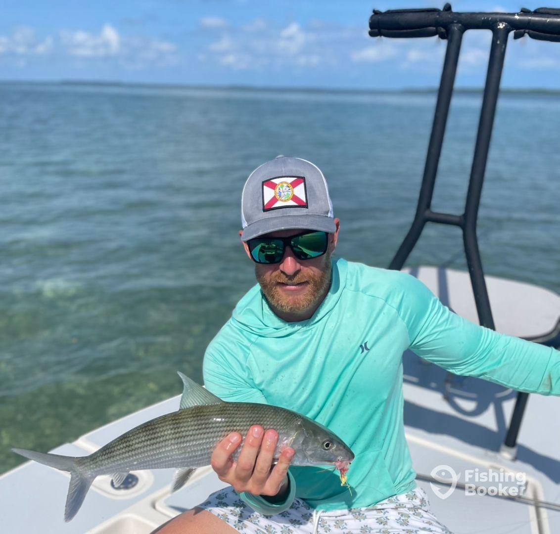 Angler displaying a large Snook while fishing from a boat in clear waters, showcasing a successful day on the water.