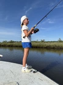 A young angler casting a line while fishing from a boat in a serene waterway, showcasing the excitement of fishing in a natural environment.