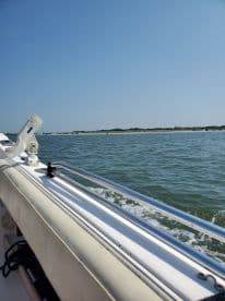 A scenic view from the side of a boat, showcasing the calm waters and shoreline, perfect for a day of fishing.