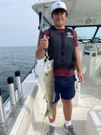 A young angler proudly displaying a Walleye while fishing on a boat, showcasing a successful day on the water.