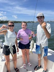A family enjoying a successful fishing trip, proudly displaying their catches of Yellowtail Snapper on a boat in a sunny coastal setting.