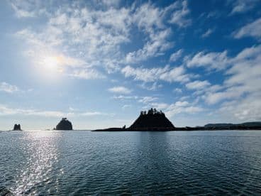 Scenic view of rocky islands under a bright sky, showcasing the tranquil waters typical of a coastal fishing environment.