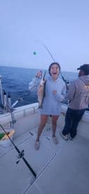 A young angler joyfully displaying a caught fish while fishing on a boat, showcasing the excitement of a successful catch.