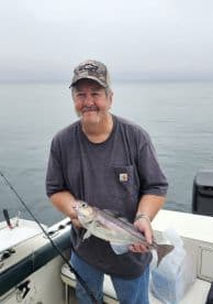 An angler proudly displaying a freshly caught fish while fishing on a calm day at sea.