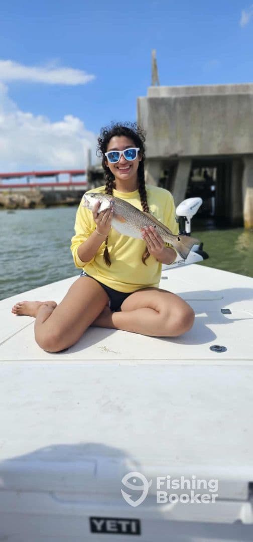 A young angler proudly displaying a caught fish while sitting on the boat, enjoying a sunny day on the water.