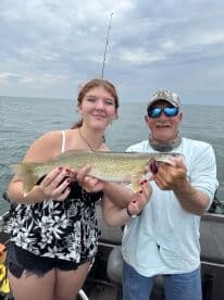 A young angler and an adult proudly displaying a Walleye caught during a fishing trip on a lake.