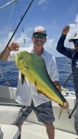 Angler proudly displaying a large Mahi Mahi while fishing offshore, showcasing a vibrant blue ocean backdrop.