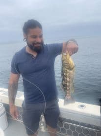 An angler proudly displaying a large striped bass while fishing on a calm day at sea.