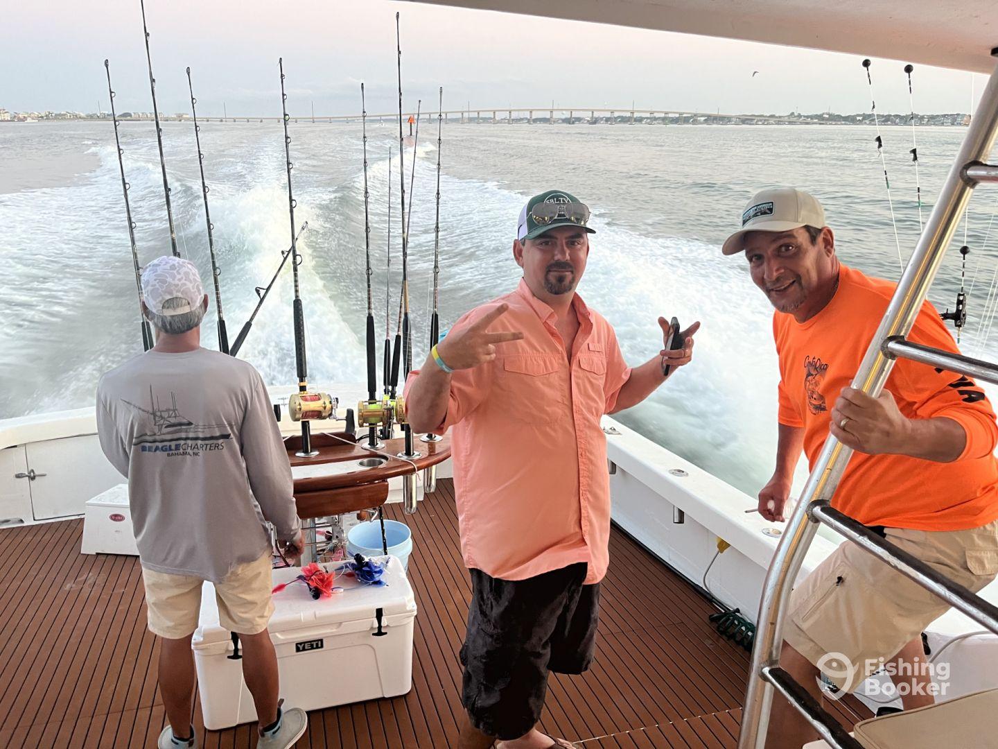 Two anglers enjoying their time on a charter boat, with fishing rods ready for action as they head out to sea.