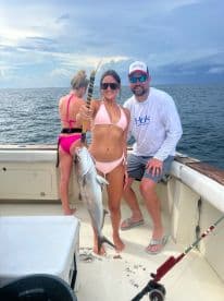 A proud angler displaying a large fish on a boat, enjoying a day of fishing in open waters.