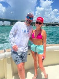 Two individuals posing on a boat with a scenic backdrop, showcasing a fun day on the water.