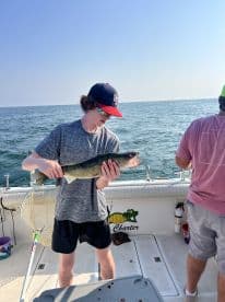 A young angler proudly displaying a Walleye on a fishing charter, with a scenic backdrop of open water.