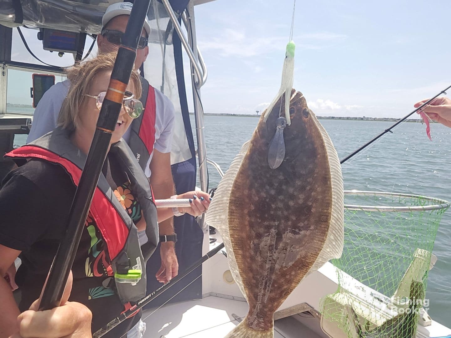 A young angler reeling in a Flounder while fishing on a boat, showcasing the excitement of a successful catch.
