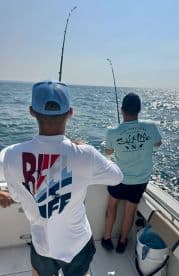 Two anglers engaged in fishing, reeling in their lines while enjoying a sunny day on the water.