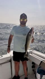 Angler proudly displaying a large Walleye while fishing on a boat in open waters.