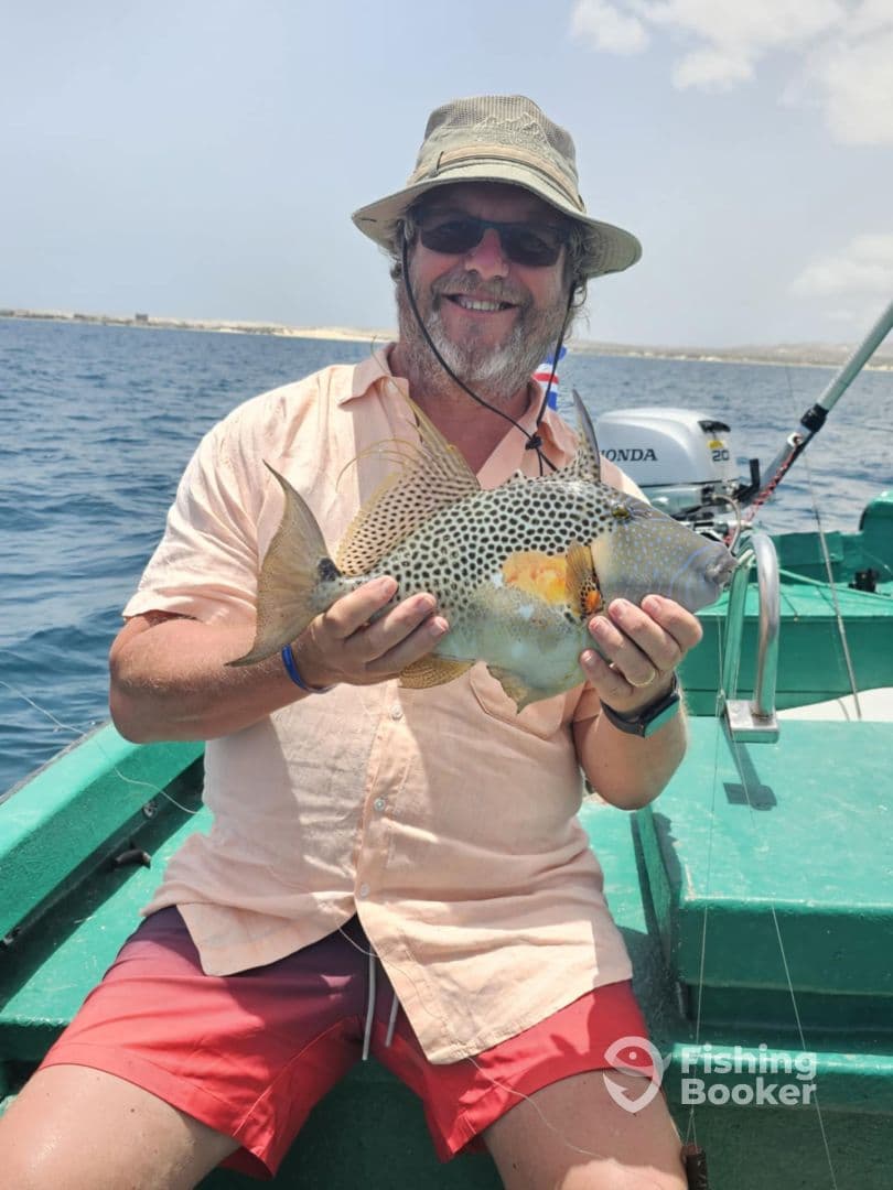 An angler proudly displaying a colorful fish while fishing from a small boat in clear waters, showcasing a successful day on the water.
