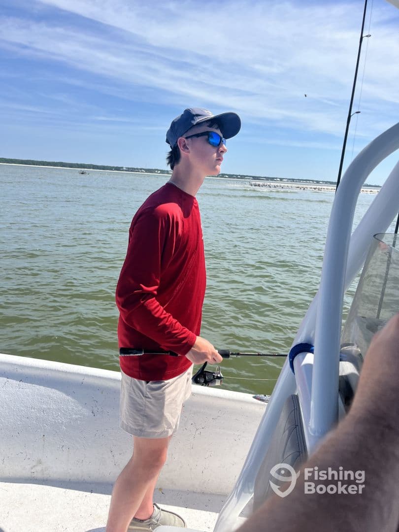 A young angler casting from the side of a boat in a coastal fishing environment, showcasing the excitement of fishing.