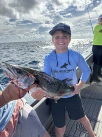 A young angler proudly displaying a large fish on a fishing boat, enjoying a day out on the water.