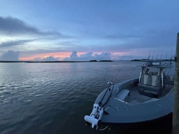 A sleek fishing boat docked at sunset, showcasing a tranquil fishing environment with calm waters and colorful skies.