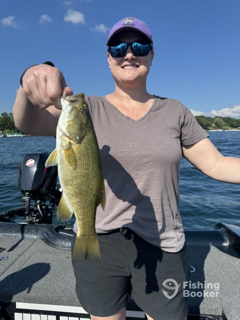 Angler proudly displaying a Smallmouth Bass while fishing on a sunny day, showcasing the excitement of a successful catch.