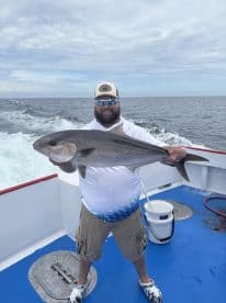 Angler proudly displaying a large Cobia on a fishing charter in open waters.