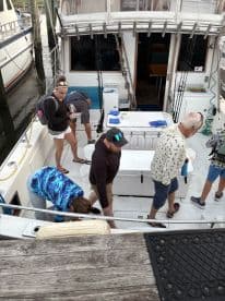 Group of anglers preparing for a fishing trip inside a spacious charter boat, showcasing the helm area and seating arrangements.