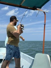 Angler actively reeling in a catch while fishing from a small boat in open water, showcasing the excitement of the fishing experience.
