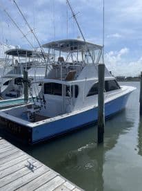 A sleek sportfishing boat named 'Reef Girl' docked at a marina, showcasing its modern design and fishing amenities.